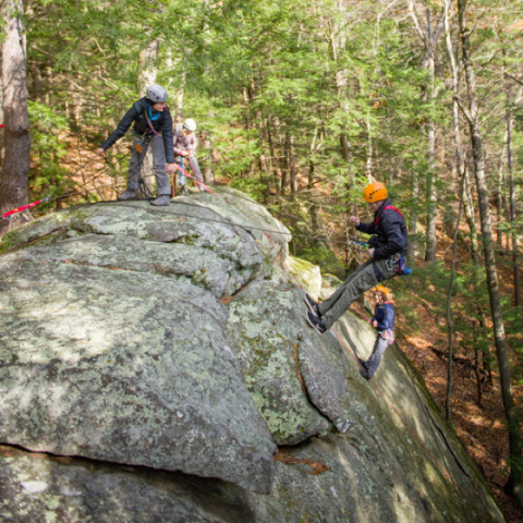 UNH Students climbing on a large rock